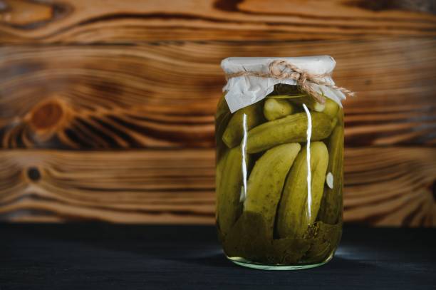 istock Pickled gherkins or cucumbers in bowl on wooden rustic table from above. 1468268841