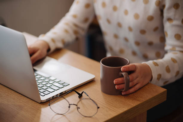 frau, die an einem laptop mit einer tasse arbeitet - weiblicher teenager allein stock-fotos und bilder