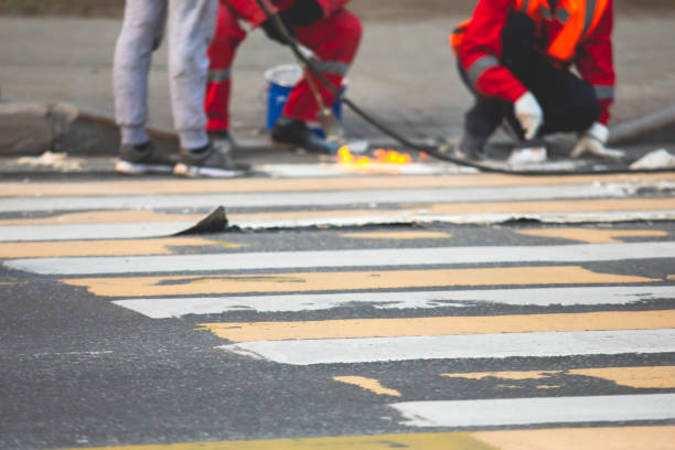 istock Process of making new road surface markings with a line striping machine, workers improve city infrastructure, demarcation marking of pedestrian crossing with hot melted paint on asphalt pavement 1468272735