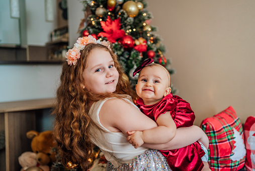 Two adorable sisters together in a Christmas decorated home