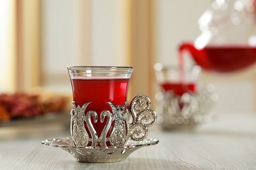 Glass of traditional Turkish tea in vintage holder on white wooden table. Space for text