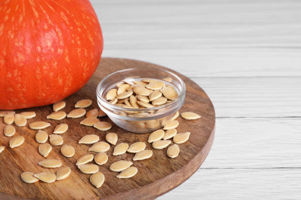 istock Fresh pumpkin and vegetable seeds on white wooden table, closeup. Space for text 1468273733