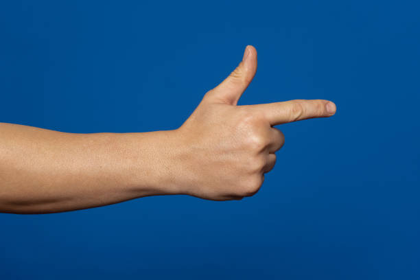istock Man's hand making shooting, gesture. Hand gun gesture on isolated blue background. Man's hand pointing a finger 1468275824