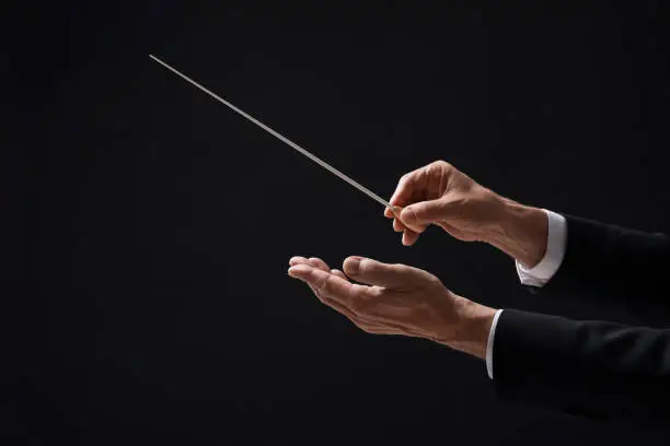 Photo of Professional conductor with baton on black background, closeup