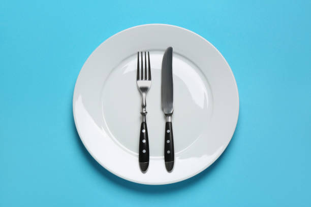 istock Clean plate with shiny silver cutlery on light blue background, top view 1468277191