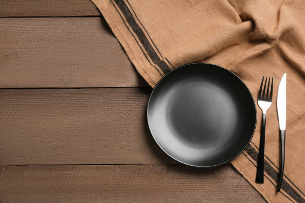 istock Clean plate and shiny silver cutlery on wooden table, flat lay. Space for text 1468277259