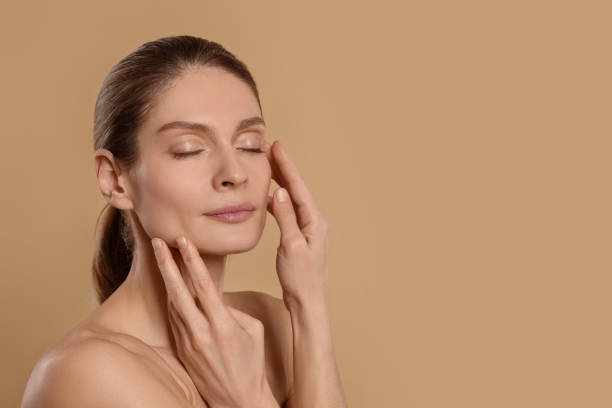 istock Woman massaging her face on beige background. Space for text 1468277265