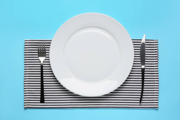 istock Clean plate and shiny silver cutlery on light blue background, flat lay 1468277429