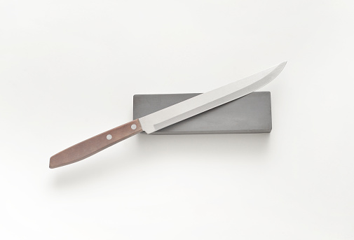 Closeup of a generic knife and slate sharpening stone on a white background.