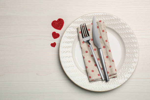 istock Plate with cutlery and decorative hearts on white wooden table for romantic dinner, top view. Space for text 1468277559