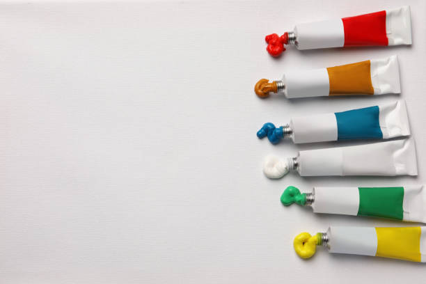 Tubes with oil paints on white canvas, flat lay. Space for text