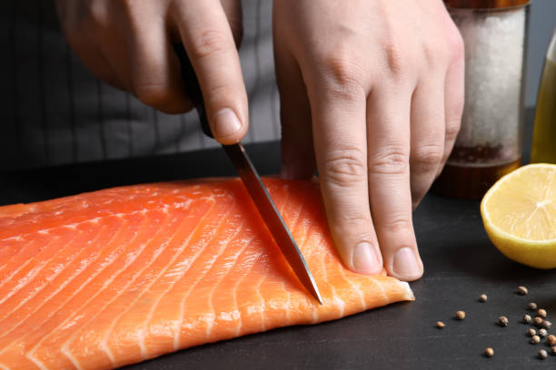istock Man cutting raw salmon at black table, closeup 1468279423
