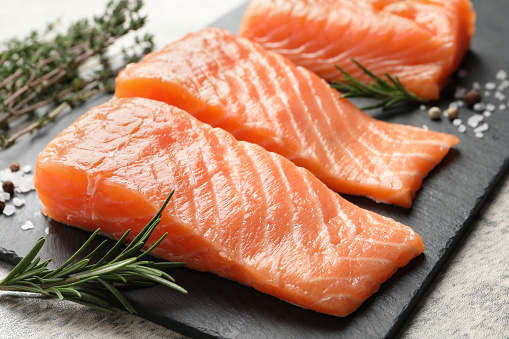 Fresh raw salmon and ingredients for marinade on light grey table, closeup