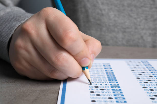 istock Student filling answer sheet at grey table, closeup. Passing exam 1468279531