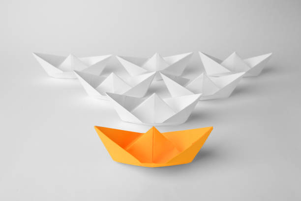 istock Orange paper boat among others on white background. Leadership concept 1468283180