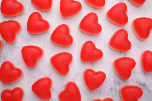 Delicious heart shaped jelly candies on white marble table, flat lay