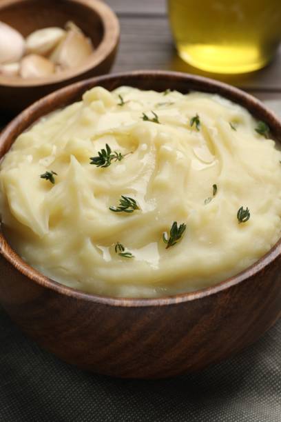 istock Bowl of delicious mashed potato with thyme on grey tablecloth, closeup 1468283437