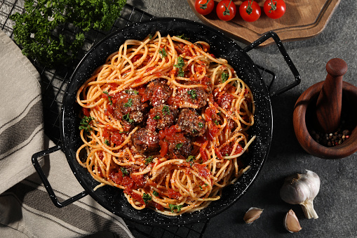 Delicious pasta with meatballs and tomato sauce near ingredients on grey table, flat lay
