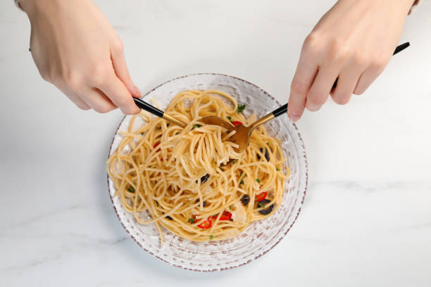 istock Woman eating delicious pasta at white marble table, top view 1468284476