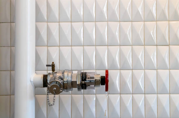 Red metal pipeline valve on the white wall