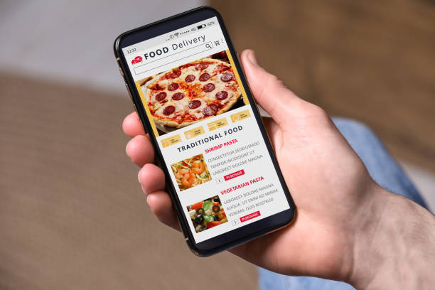 istock Food delivery service. Man choosing dish from menu on site using smartphone indoors, closeup 1468285865