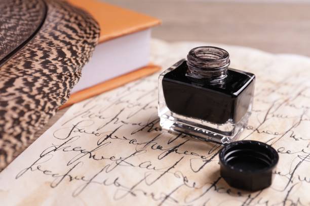istock Open inkwell, feather, book and vintage parchment with text on table, closeup 1468285920
