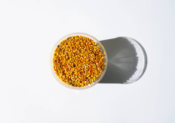 Top view of multicolor pollen graines in plastic bowl on white background