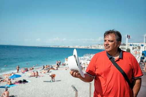 Man in red shirt at Nice, France, city beach promenade on summer day