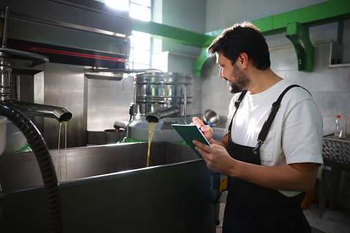 Worker processing olives in machine at factory. Candid photos of realistic man man working in olives factory