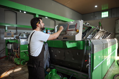 Worker processing olives in machine at factory. Candid photos of realistic man man working in olives factory