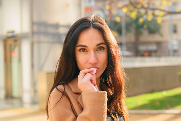 istock Young woman eats a candy while looking at camera on the street 1468294173