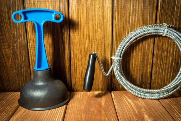 istock Clean plastic plunger with blue handle, pipe wrench and cable on wooden background. 1468297289