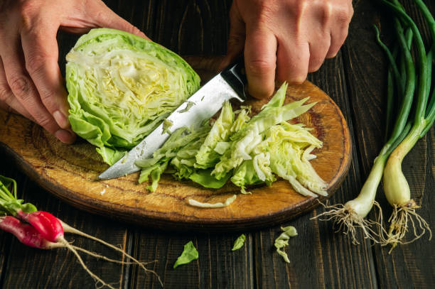 istock Slicing cabbage on a cutting board. Delicious salad for dinner with fresh vegetables. Hands of a chef with a knife while cooking in a kitchen. 1468298029