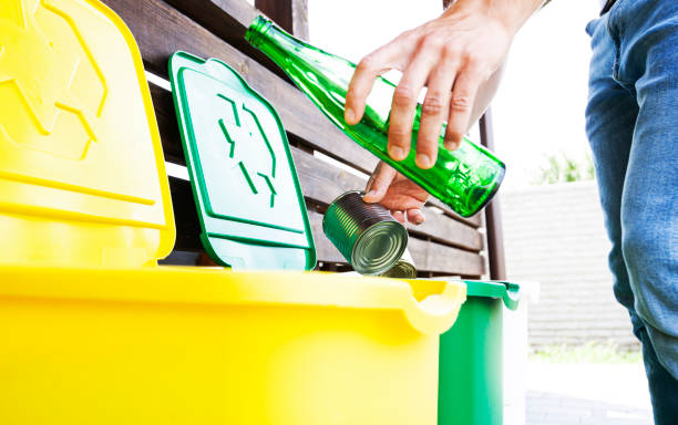 istock Man throwing the glass bottle andtin can into differennt dustbins for sorting trash 1468299198