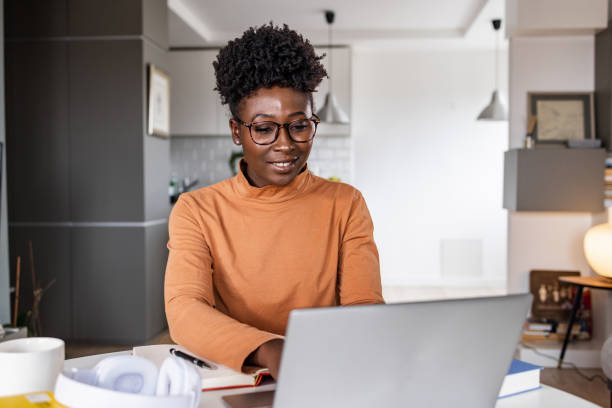 una giovane donna nera sta lavorando al portatile - laptop using laptop studying working at home foto e immagini stock