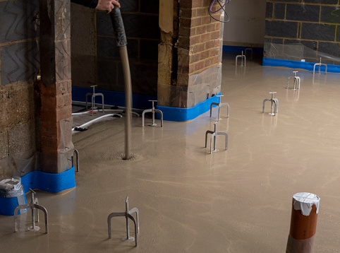 Flooring screed being poured out over under floor pipework