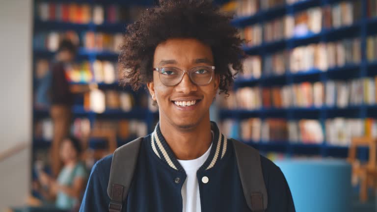 Portrait of afro-american male student smiling at camera in campus library