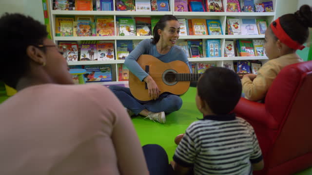 Happy teacher signing to her students during music class at the kindergarten