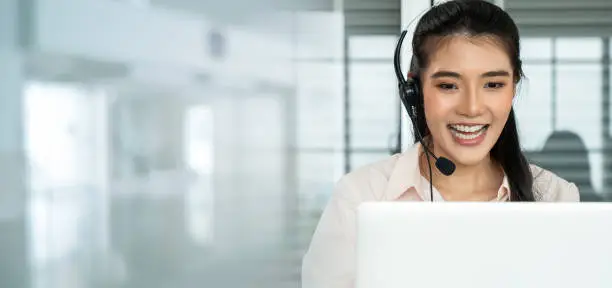 Businesswoman wearing headset working actively in office . Call center, telemarketing, customer support agent provide service on telephone video conference call.