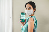 Young Asian woman shows vaccine passport on mobile phone to validate travel permission by the digital document
