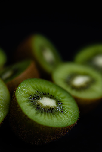 photograph of cut kiwis on black background with great detail and bright colors, space for copying.