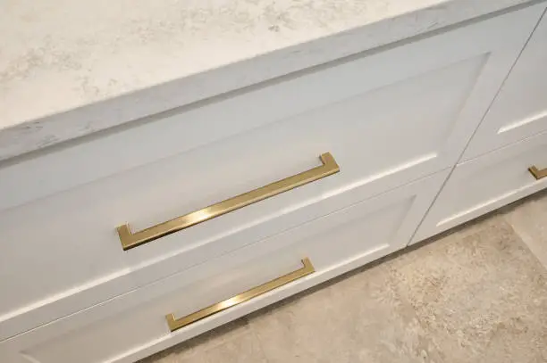 closeup angled view of cabinet drawers with gold hardware and stone countertop
