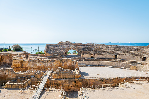 Wide-angle view of the ruins of the Roman amphitheater in Tarragona, built in the 2nd century AD, with the Mediterranean Sea in the background.