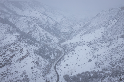 A mountain road winding through a canyon during a snowy winter whiteout in the Front Range of the Rockies in Colorado.