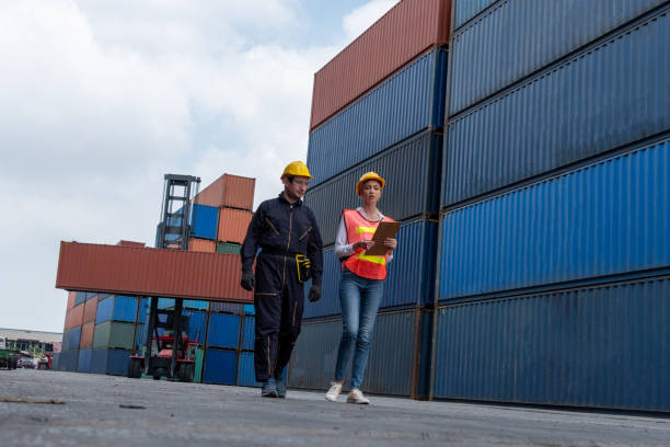istock Industrial worker works with co-worker at overseas shipping container yard . Logistics supply chain management and international goods export concept . 1468315035