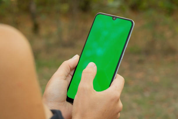 istock hands holding phone with green screen in summer park close up 1468315787