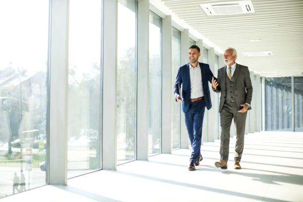 istock Senior and junior management business people walking through hallway and talking 1468318414
