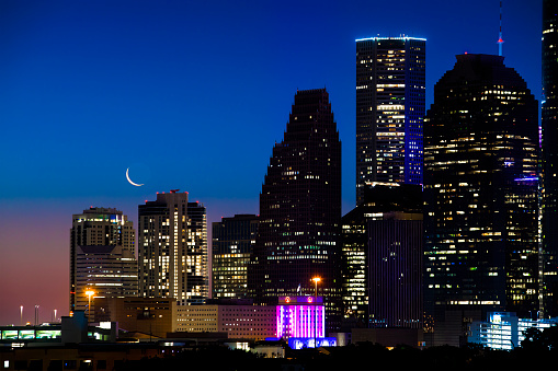 Looking east towards downtown Houston Texas before sunrise in late May 2022 and seeing a sliver of the new moon.