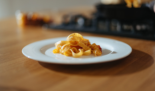 Tasty homemade tagliatelle on a plate on the wooden table in the kitchen.