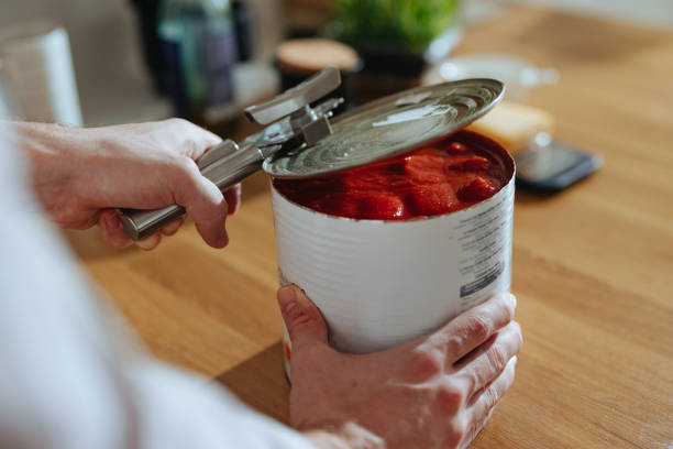 foto de primer plano de las manos del hombre abre la tapa del puré de tomate enlatado - food industry manufacturing human hand fotografías e imágenes de stock